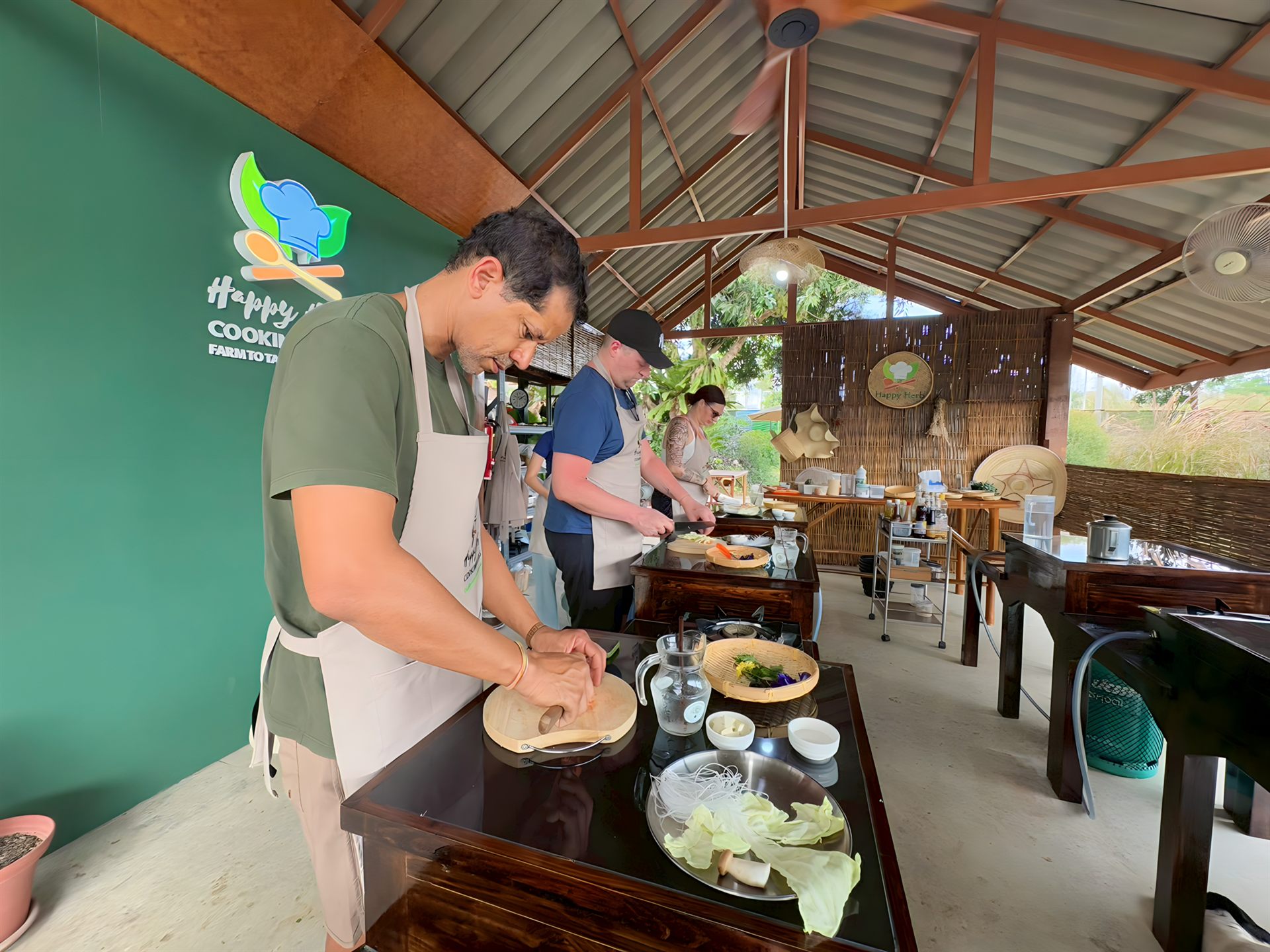 Travelers enjoying the group Thai cooking class experience at Happy Herb in Chiang Mai